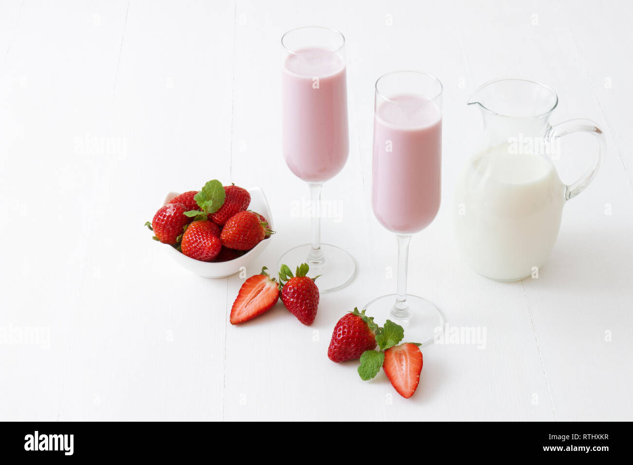 Batido de Fresa. 2 vasos de leche malteada de fresa, vidrio jarra de leche,  tazón de porcelana con fresas embellecido con algunas fresas real  Fotografía de stock - Alamy