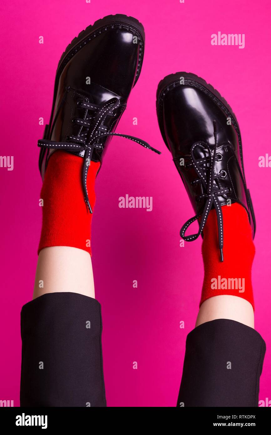 Piernas femeninas en calcetines rojos y elegantes zapatos negros sobre un  fondo de color rosa. tendencias de la moda, zapatos de mujer hermosa  Fotografía de stock - Alamy