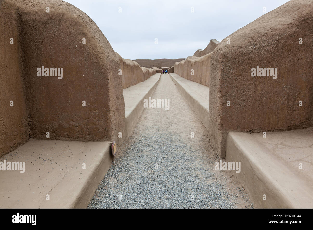 Inmensos muros de la ciudad de Chan Chan, capital del reino Chimú, visitados por turistas que caminan por senderos en su interior. Foto de stock