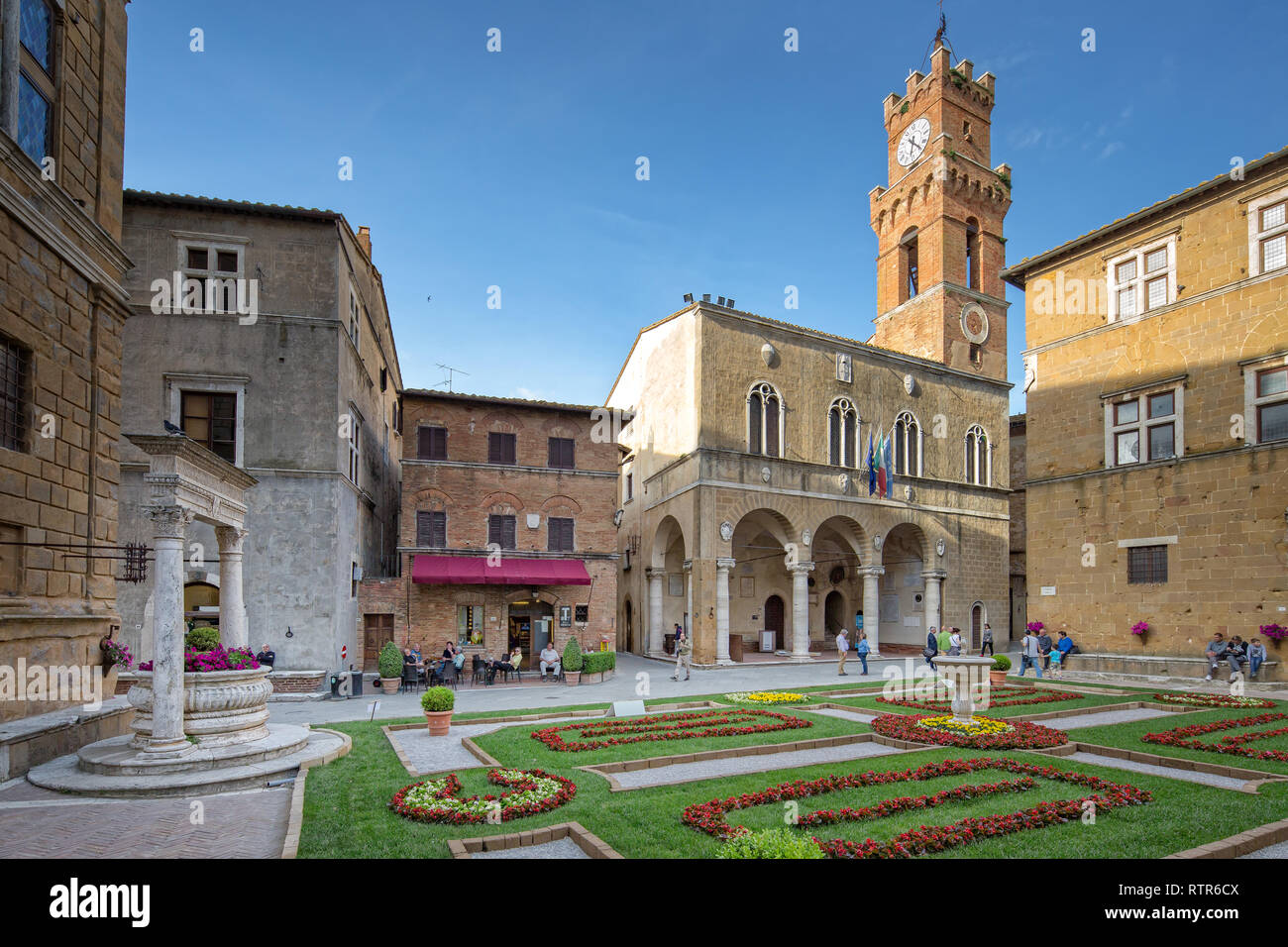 Pienza, Toscana/Italia - 10 de mayo de 2016: Piazza Pio II., idílica plaza con una fuente, ayuntamiento y una pequeña cafetería en Pienza. Foto de stock