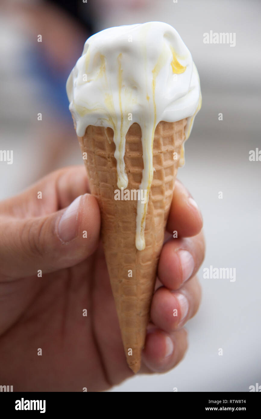 Cono de helado, la fusión en una mano de hombre Foto de stock