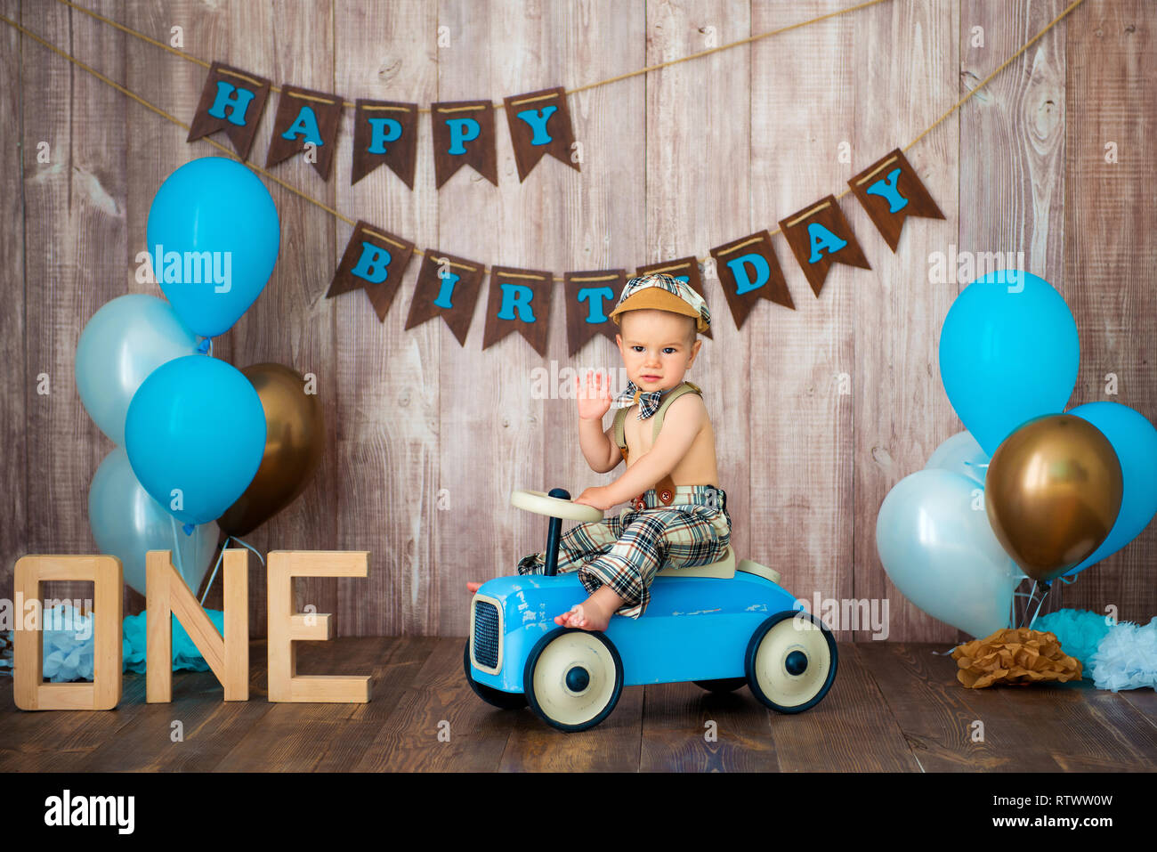 Little Boy kid caballero en traje retro con tirantes y cap está sentado en  un coche de madera. Fiesta infantil con globos Feliz cumpleaños, 1 año  Fotografía de stock - Alamy