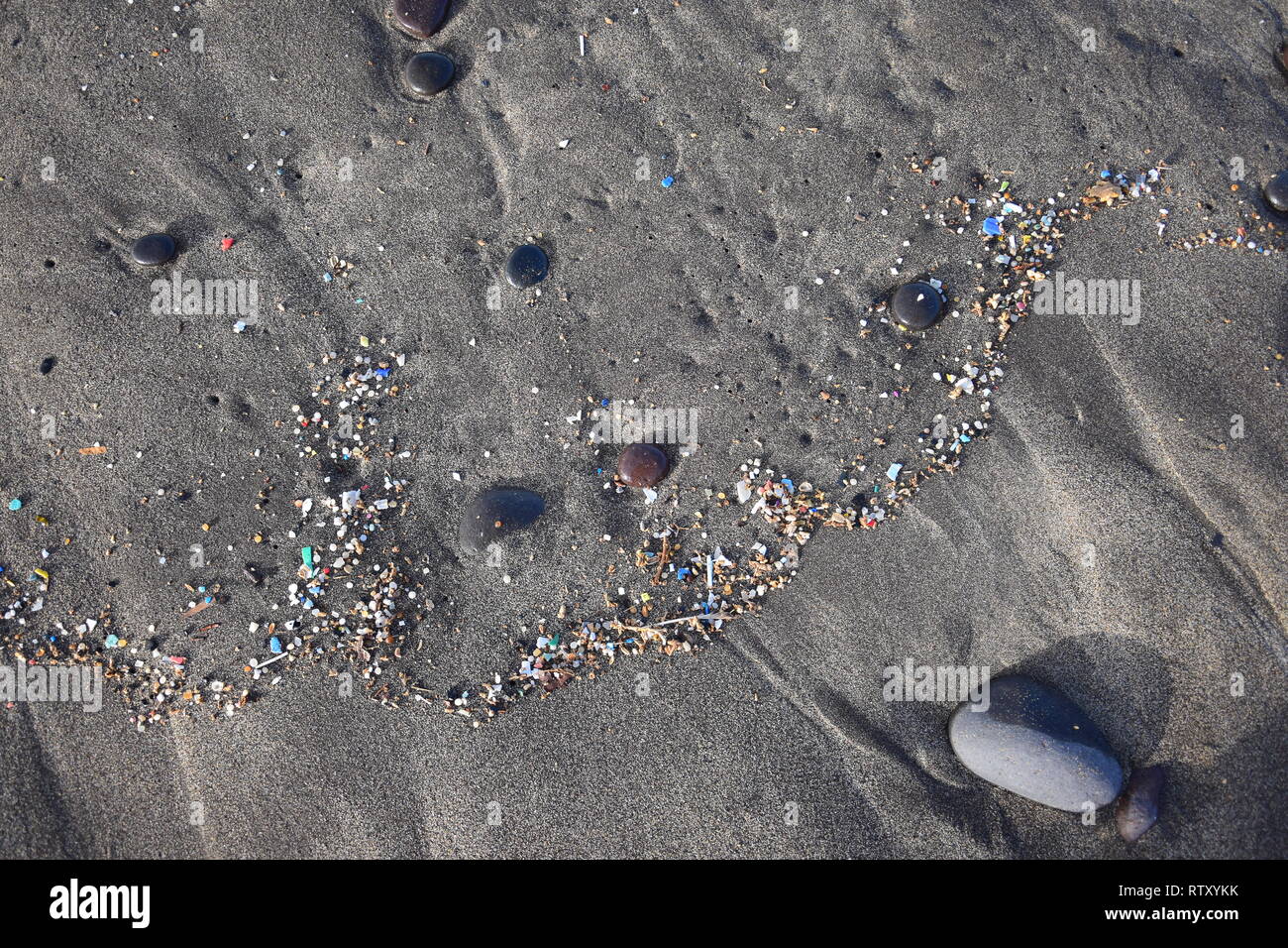 Pequeñas piezas de plástico y microplastics en la arena de la playa de Famara, Lanzarote, España. Foto de stock