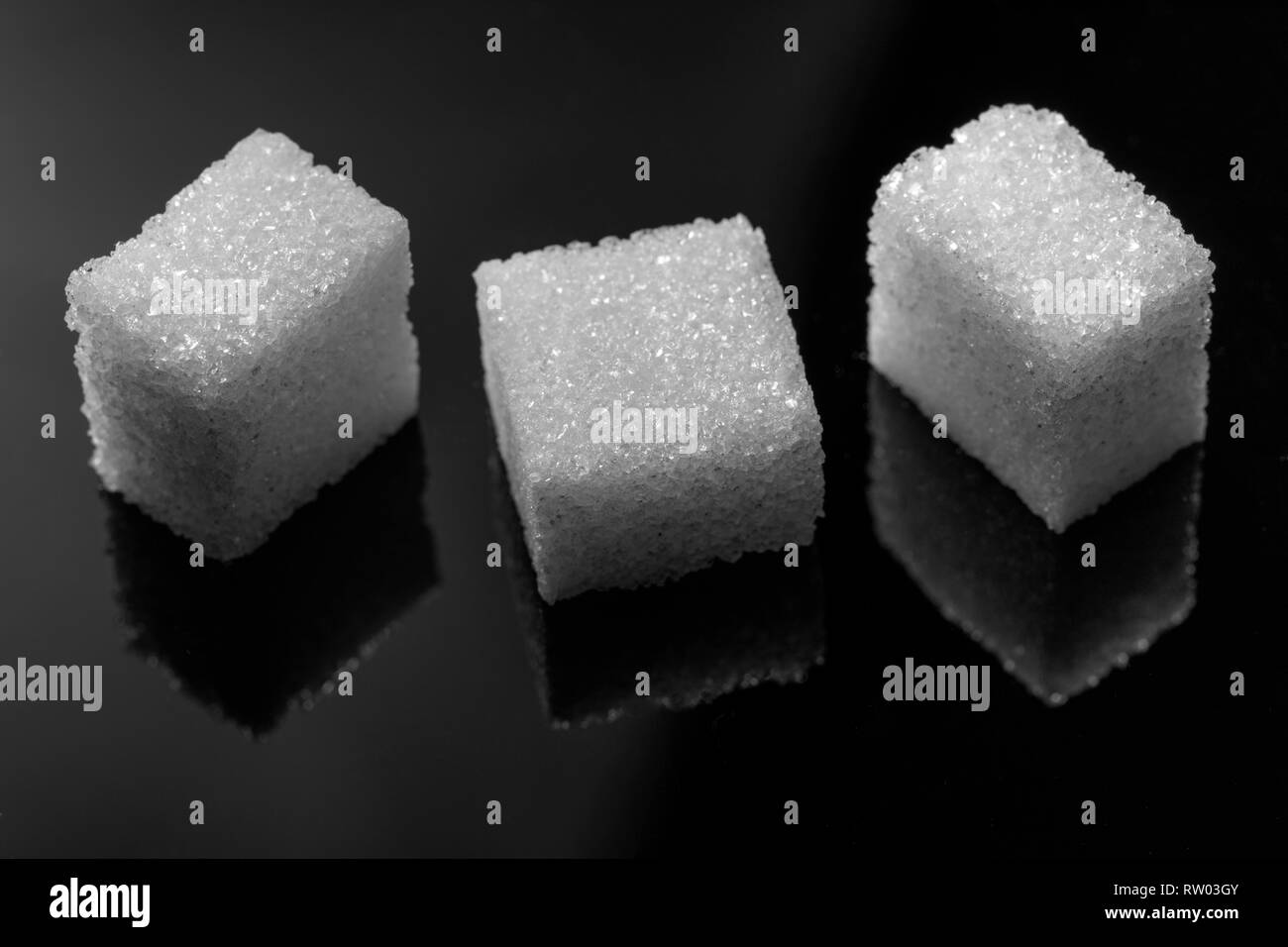 Tres pedazos cubo de azúcar sobre fondo negro Foto de stock