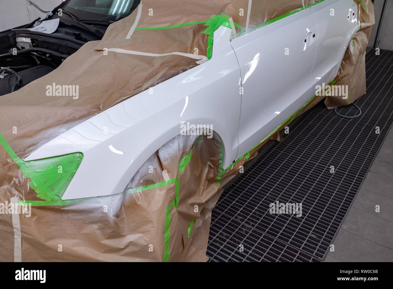El coche tras el accidente en la cámara para la reparación de carrocería de  automóviles está parcialmente cubierto con papel y pegado con cinta  adhesiva verde para pintar el Fotografía de stock -