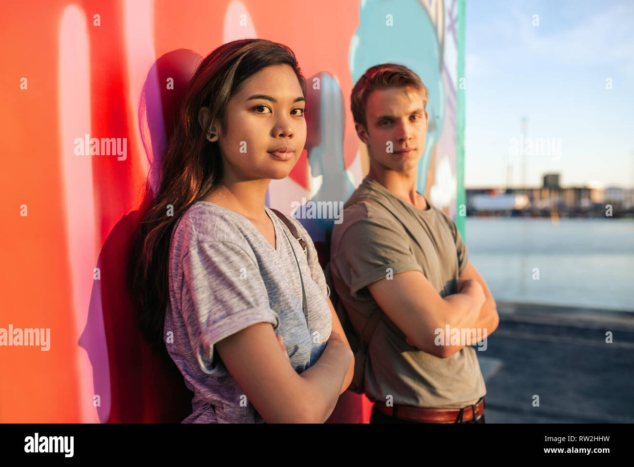 Cool pareja joven de pie por las pintadas en la ciudad Foto de stock