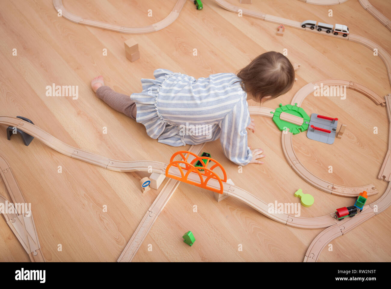 Cute kid jugando con trenes de juguete en casa en carretera Foto de stock