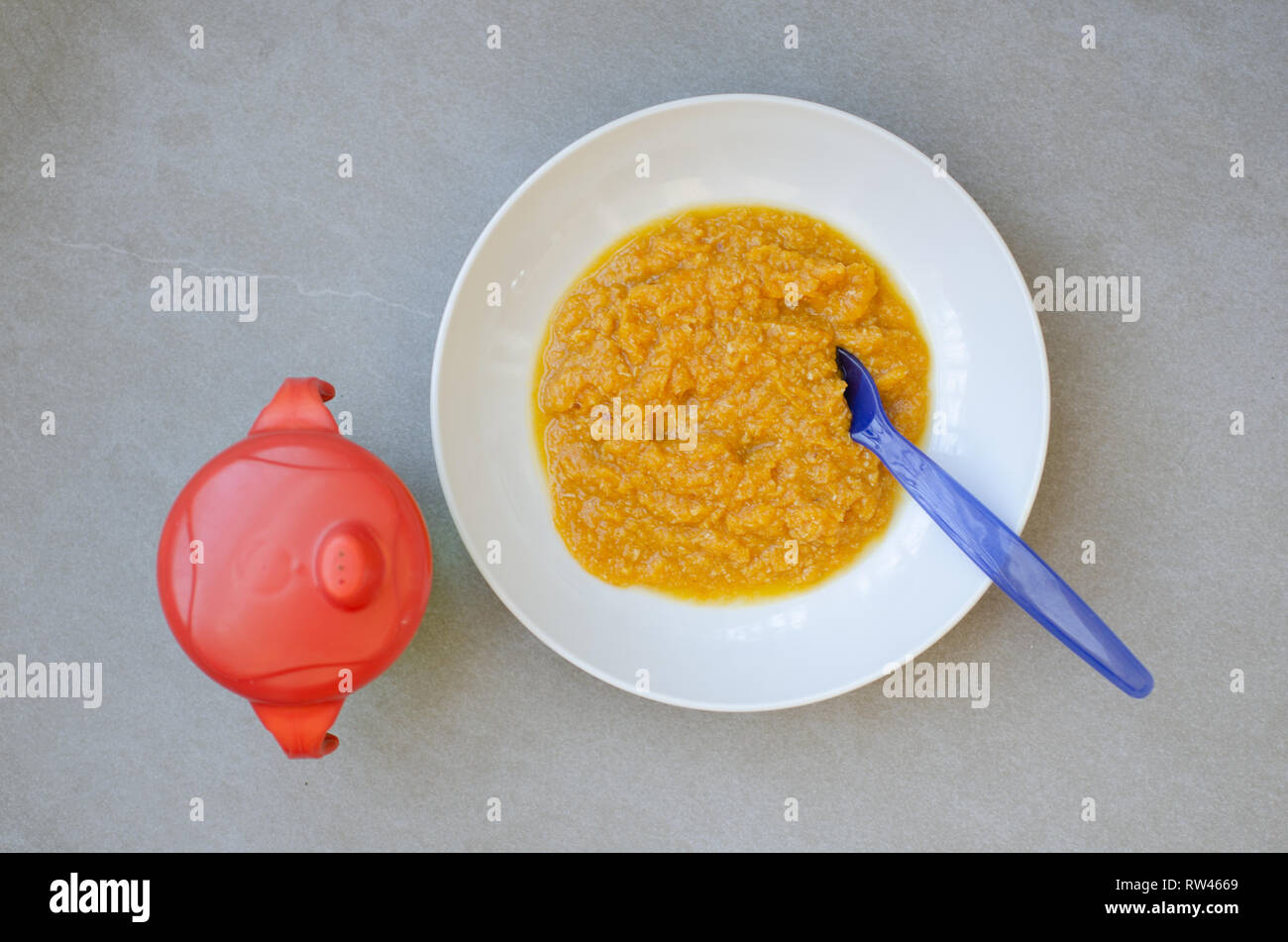 Tazón de comida para bebé hechas con puré de zanahoria y pollo Foto de stock