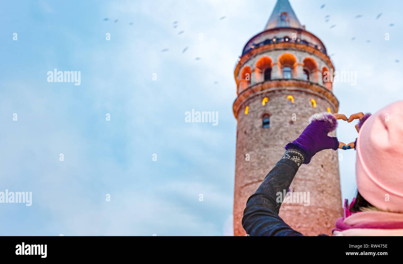 Bella mujer viajero hace de forma de corazón con manos con vista de la torre de Galata sobre antecedentes en Estambul, Turquía Foto de stock