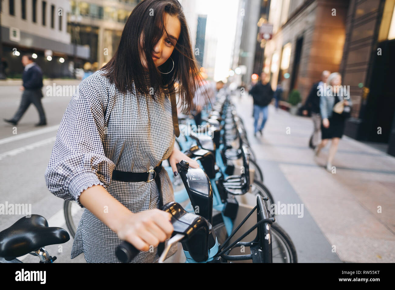 Chica alquilando una bicicleta de ciudad desde un soporte de la bici Foto de stock