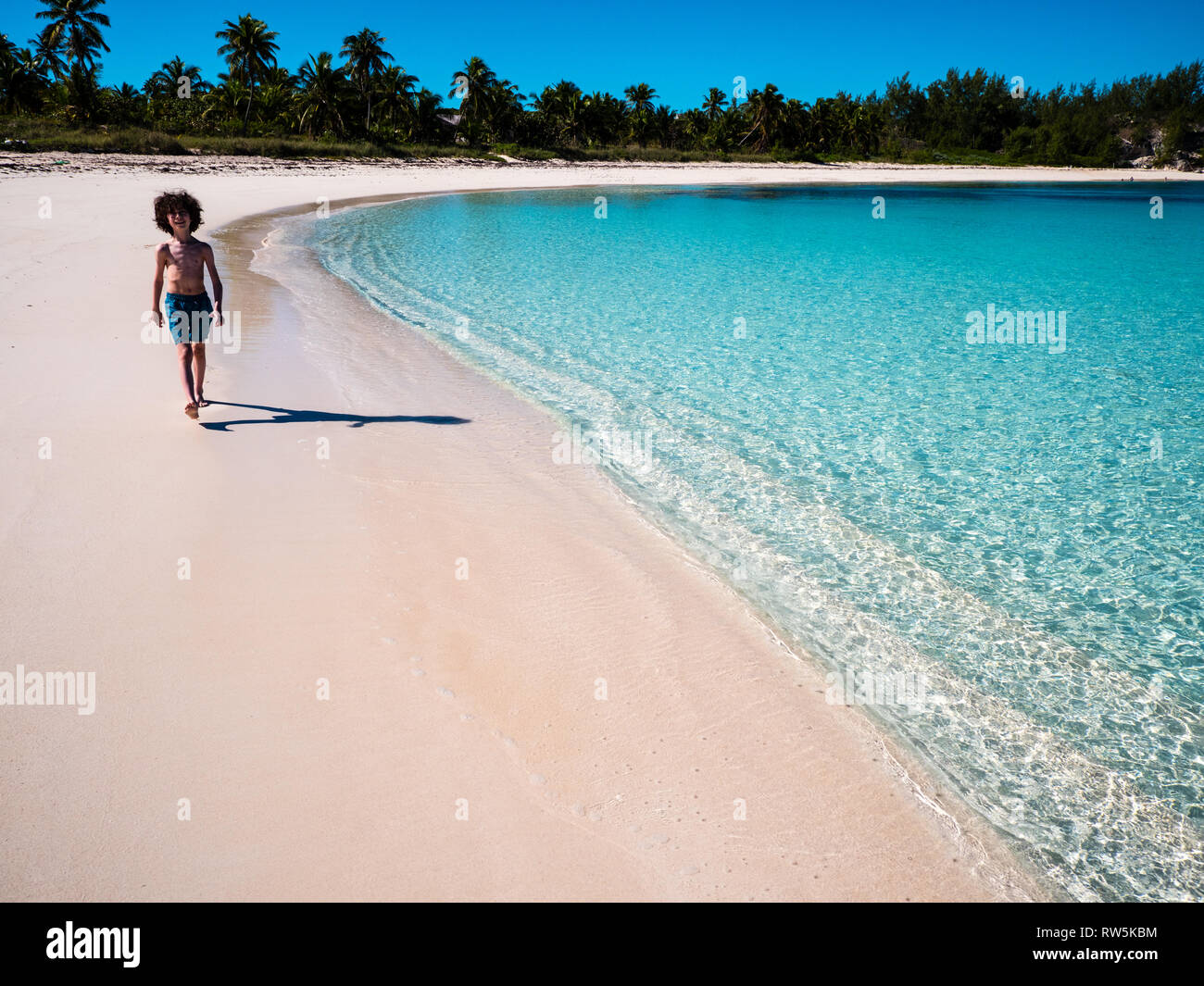 Muchacho caminando junto al mar, Playa Tropical, Calas gemelas Playa, Eleuthera, las Bahamas, El Caribe. Foto de stock
