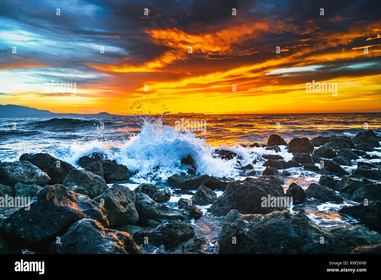 Puesta de sol brillante bajo la tormenta con olas del mar salpica Foto de stock