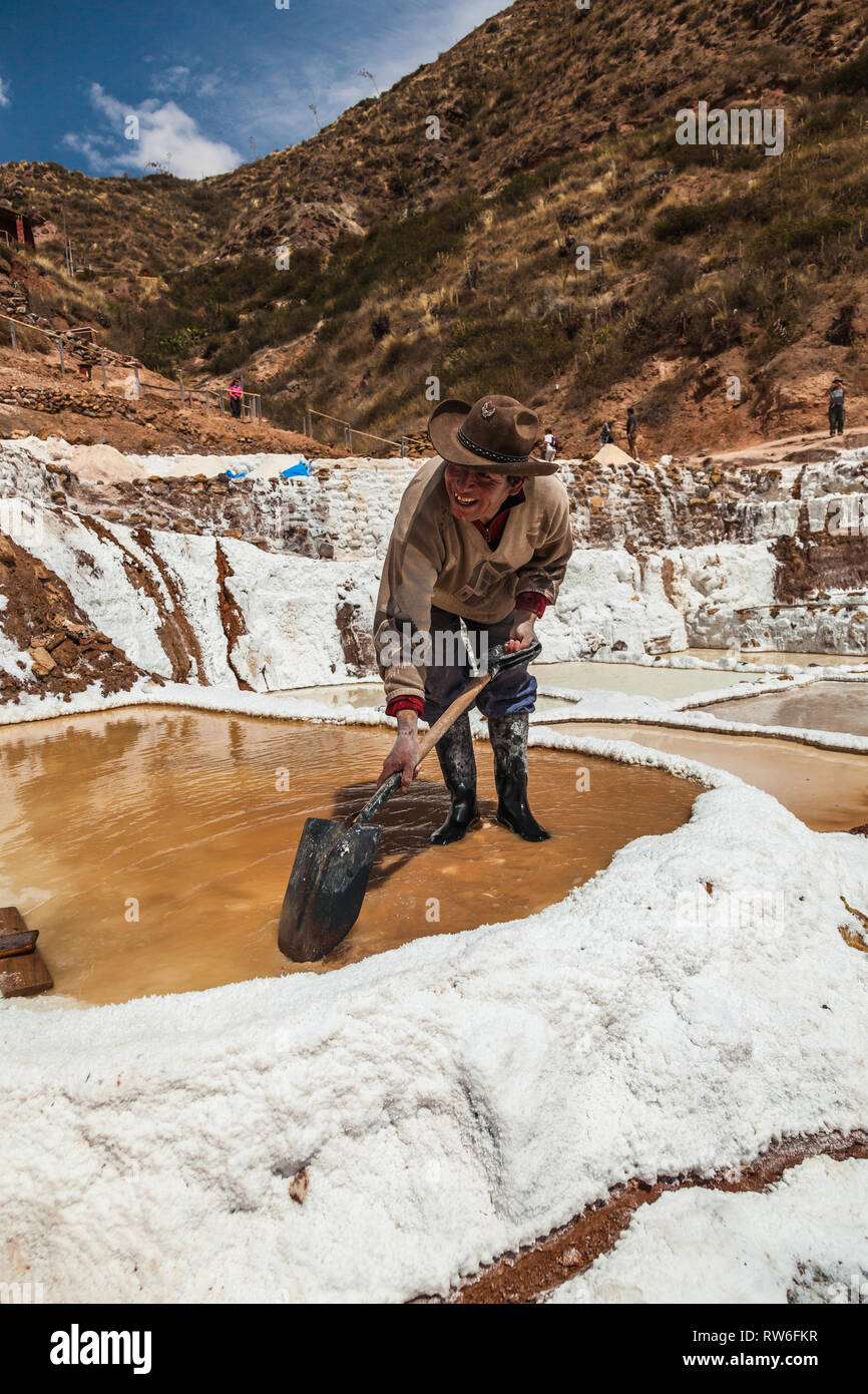 Maras, Cusco, Perú, agosto de 2018: un trabajador no identificado extrae la sal de las balsas de evaporación en maras, una mina que ha sido explotado por ciento Foto de stock