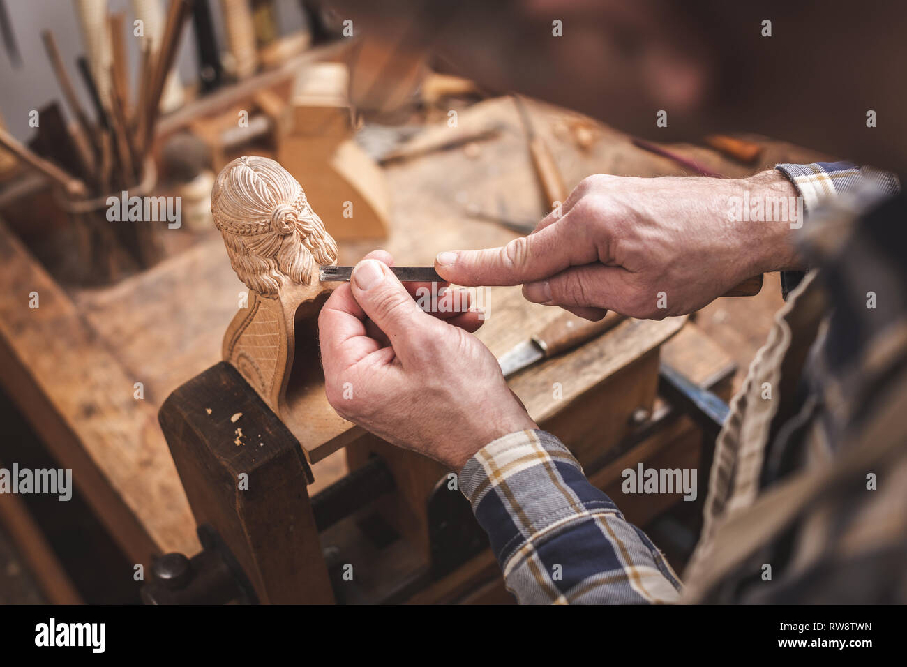 Escultor de madera en un banco de madera tallando una figura Foto de stock