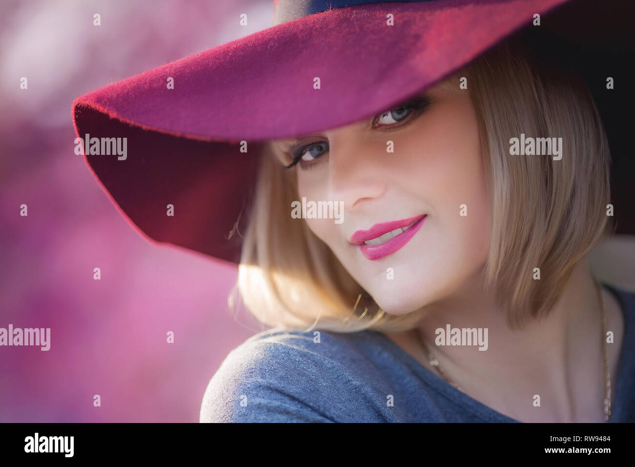 Mujer joven sonriente en el fondo del jardín rojo, copia el espacio. Foto de stock