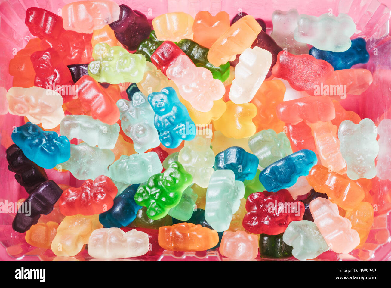 Un close-up de tres filas de colores brillantes ositos, fotografiado sobre un fondo de color rosa con luz de estudio de la adormidera. Foto de stock
