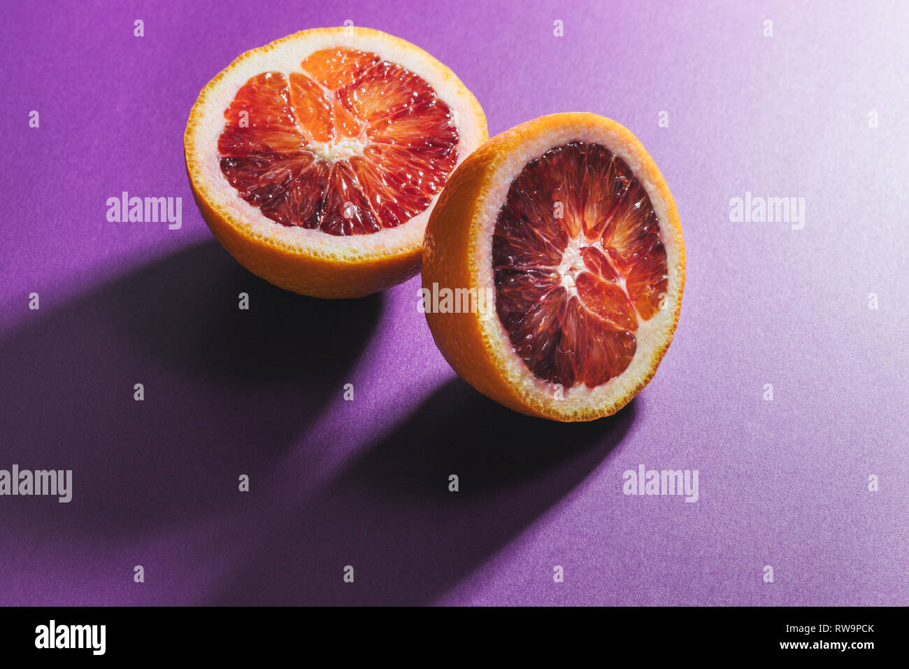Un gráfico todavía la vida de rodajas de naranja de sangre sobre un fondo de colores, fotografiado con disco luces y sombras en el estudio. Foto de stock