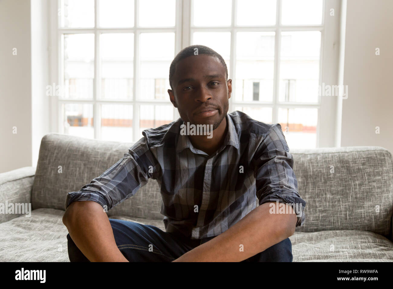 Hombre afroamericano sentarse en el sofá haciendo videollamada Foto de stock