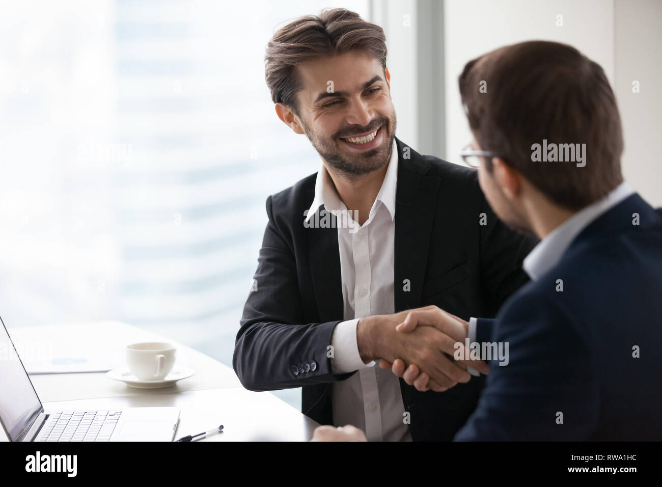 Satisfecho empresario feliz en traje handshake business partner haciendo frente Foto de stock