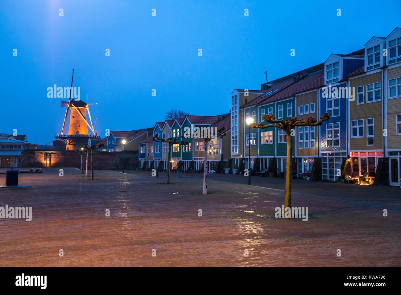 Coloridas casas con molino De Hoop al anochecer, Hellevoetsluis, Holanda Meridional, Países Bajos Foto de stock