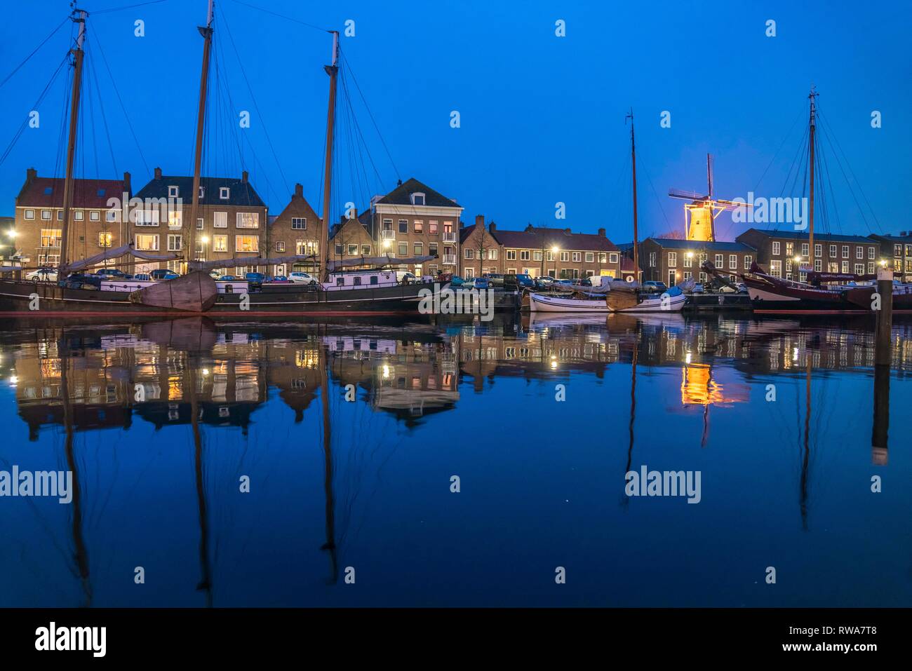 Vista de la ciudad con el puerto y el molino de viento de Hoop al anochecer, Hellevoetsluis, Holanda Meridional, Países Bajos Foto de stock