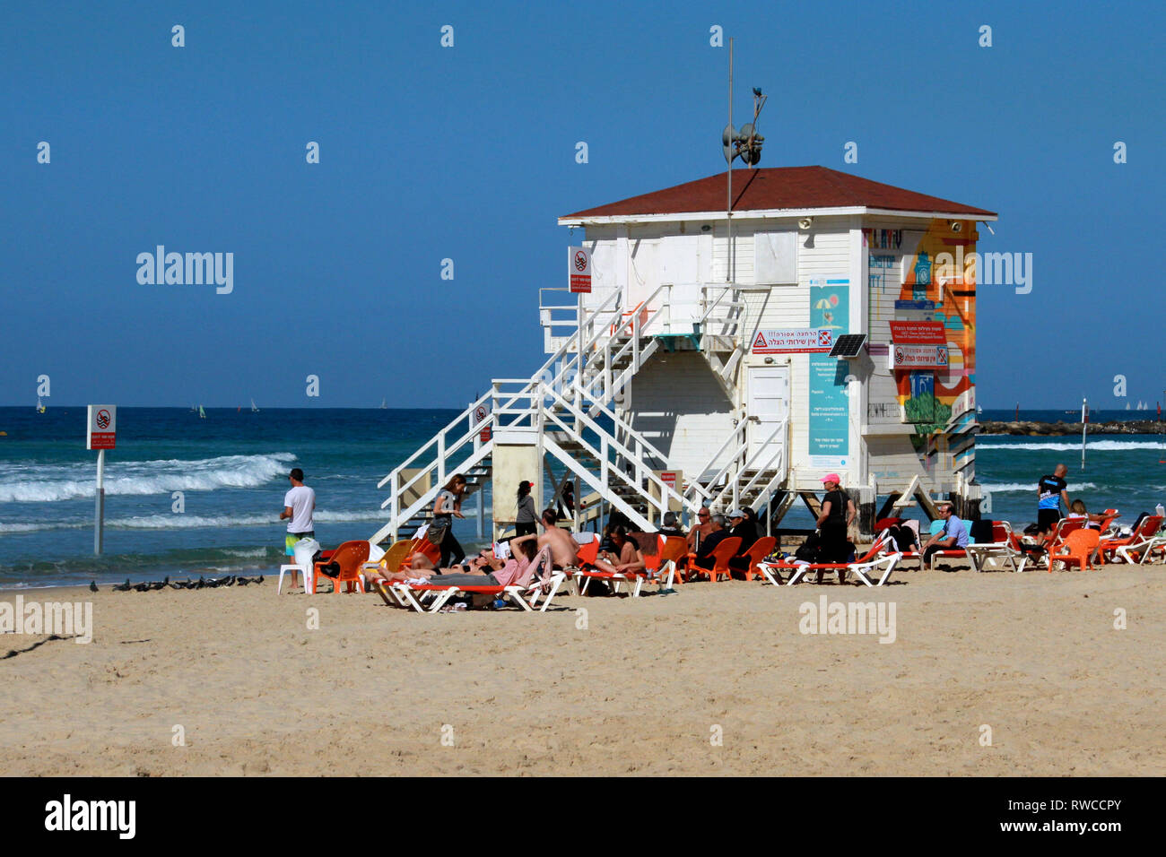 Salón Beachgoers cerca de una cabaña de playa blanca a orillas del Mar Mediterráneo en Tel Aviv el Shabat. Foto de stock