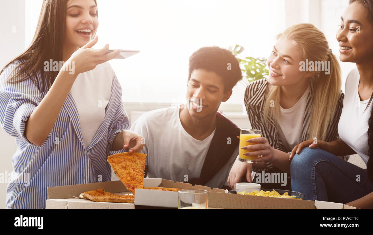 Joven blogger toma de fotografía de la pizza, habiendo partido con amigos Foto de stock