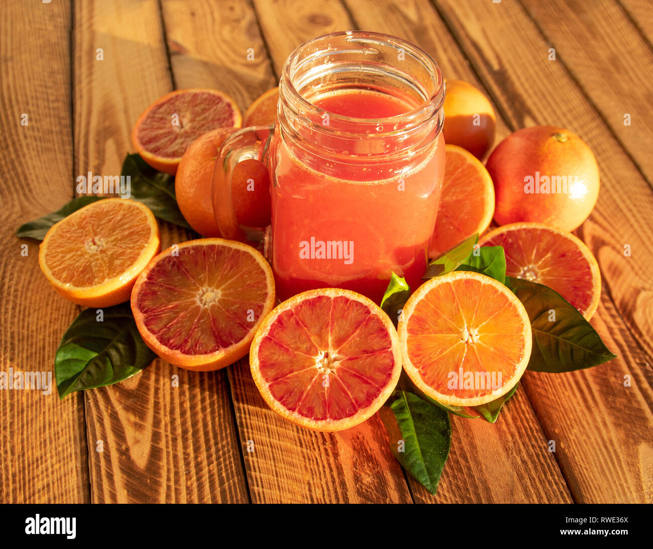 Composición brillante con naranjas y jugo de frutas rojas de sangre fresca de naranjas, disparó al aire libre bajo el sol Foto de stock