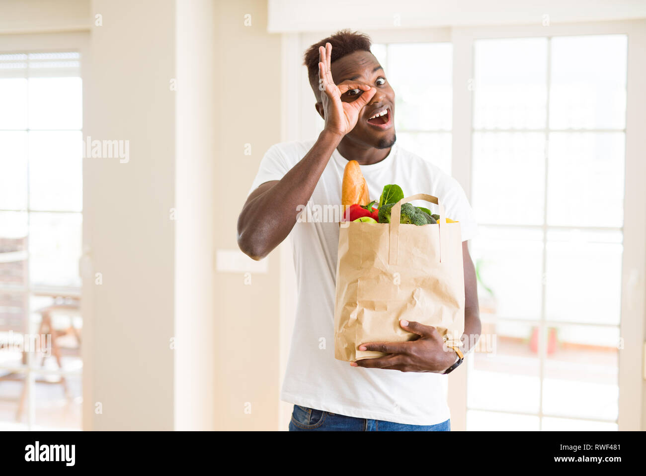 Hombre afroamericano la celebración de bolsa de papel llena Hombre afroamericano la celebración de bolsa de papel llena