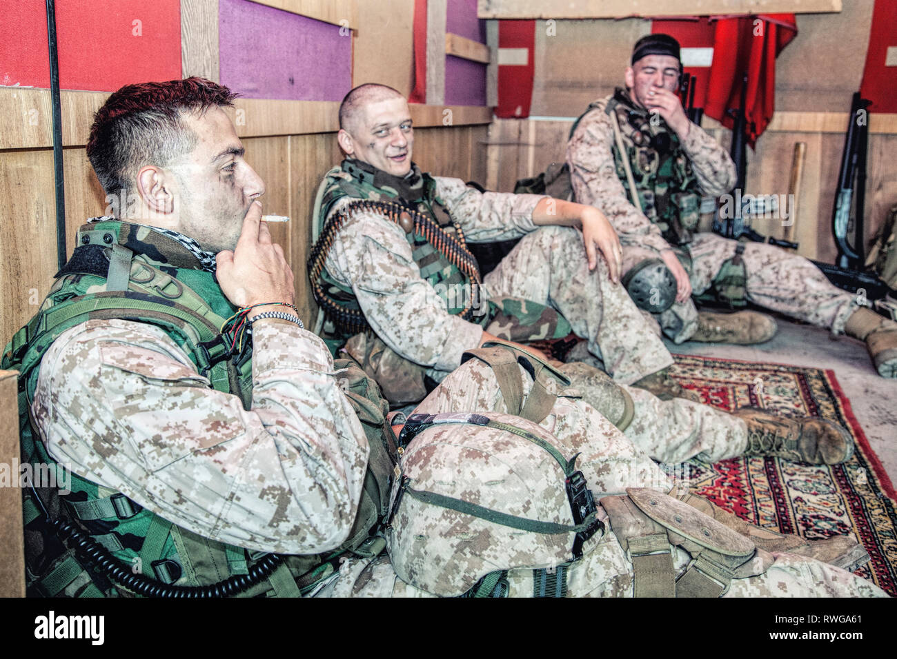 Infantes de Marina de los Estados Unidos hablando y descansando mientras está sentado en el piso en su puesto de combate. Foto de stock