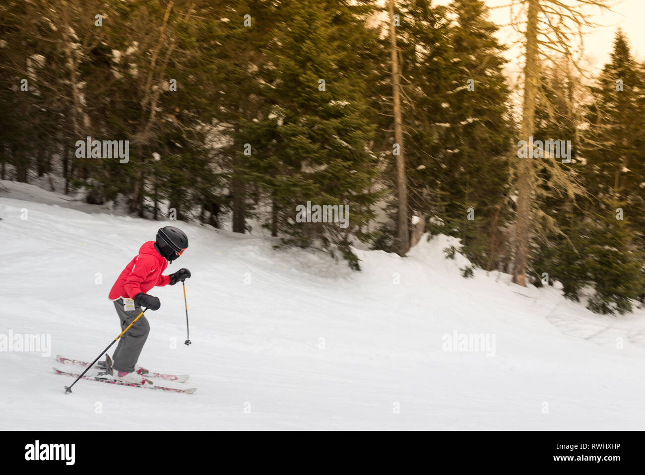 Un niño llevaba esquís engranaje de los deportes de invierno a bajar por una montaña Foto de stock