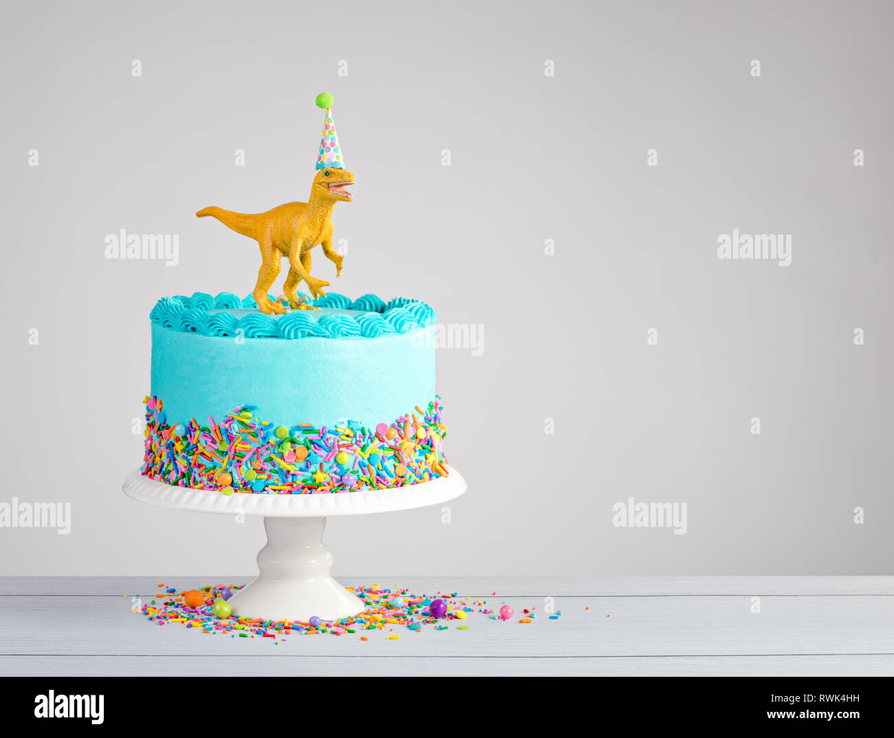 Buttercream azul pastel de cumpleaños con coloridos dinosaurios de juguete  y espolvorea sobre un fondo gris claro Fotografía de stock - Alamy