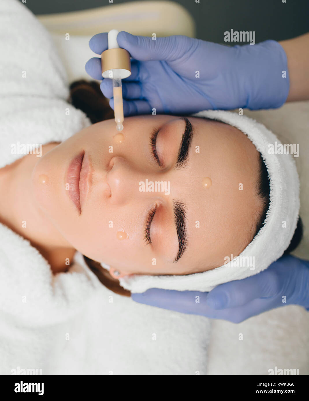 Esteticista aplicando suero para el rostro femenino. Suero tratamiento piel Foto de stock