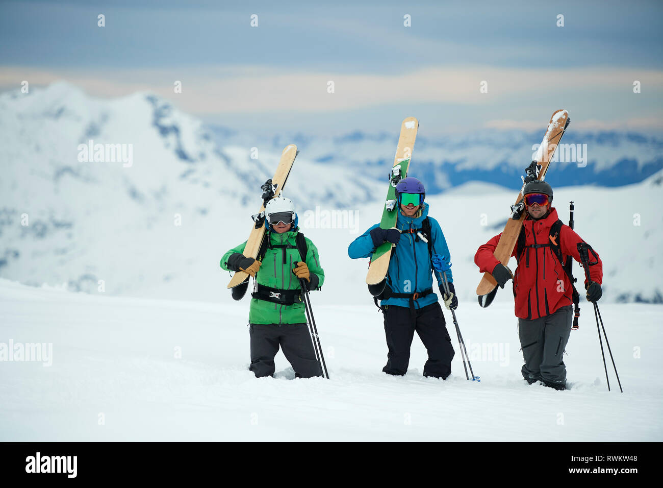 Paisaje con tres esquiadores masculinos llevar esquís, retrato, Alpe-d'Huez, Rhône-Alpes, Francia Foto de stock