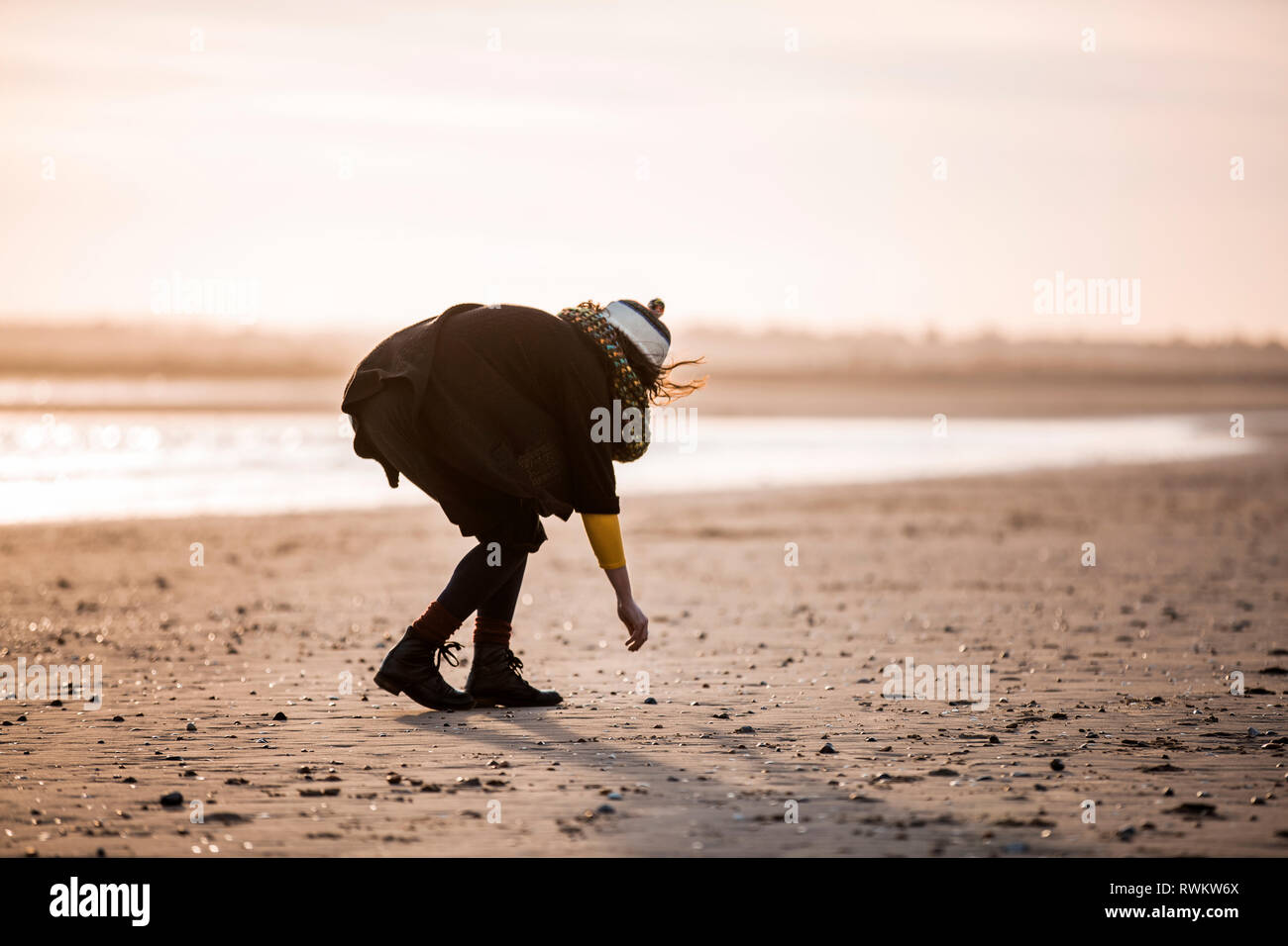 Mujer recogiendo guijarros en la playa Foto de stock