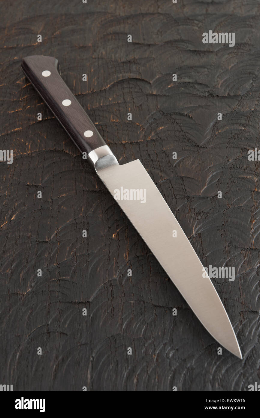 Pequeña cocina cuchillo sobre la tabla de cortar de madera oscura. Foto de stock