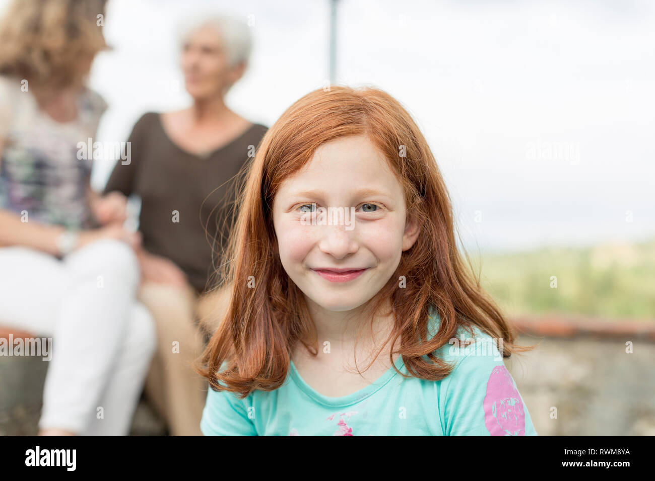 Chica pelo rojo con madre y abuela, en el fondo, Retrato Foto de stock