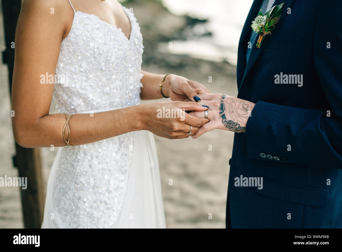 Novia poniendo en anillo de bodas del novio en lakeside, sección intermedia Foto de stock