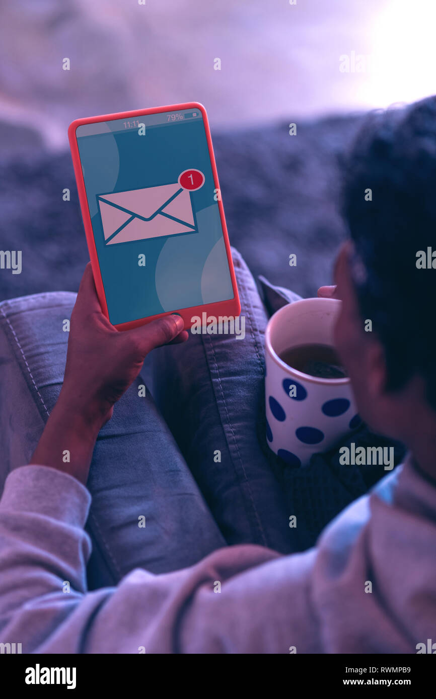 Mientras joven beber té, recibiendo el mensaje sobre la tableta. Foto de stock