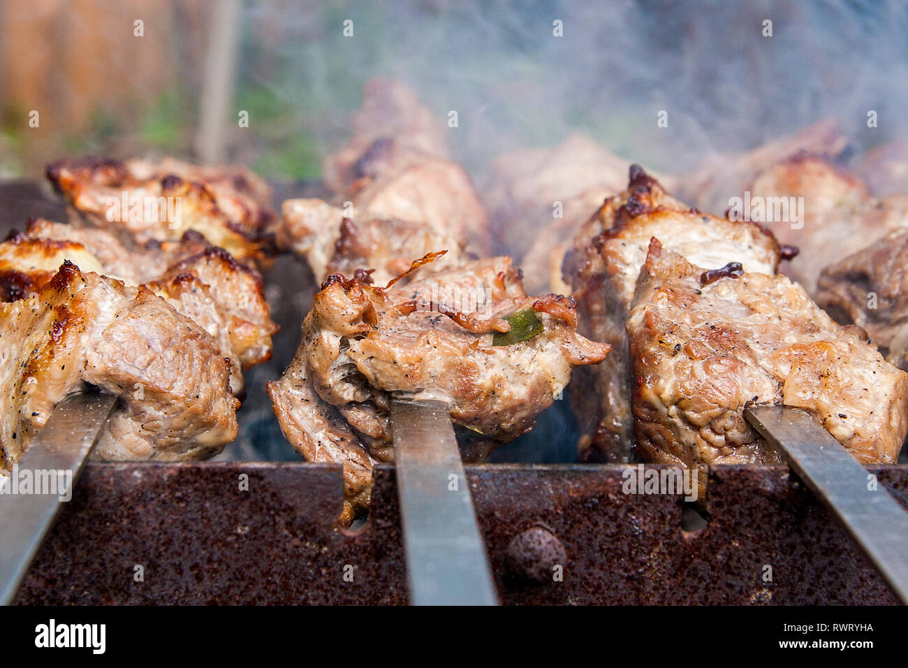 Parrilla de cocción de kebab en pincho de metal. Hecha pinchito de cubos de carne en las brochetas durante la cocción en el mangal en carbón al aire libre. Parrilla Foto de stock