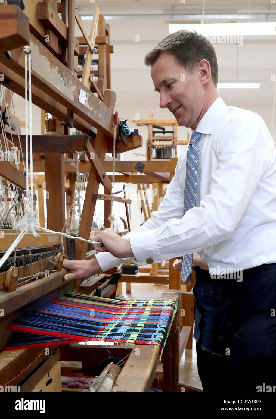 Secretaria de Relaciones Exteriores Jeremy Hunt opera un telar durante una visita a la escuela de los Textiles y el diseño en el campus de la Universidad Heriot Watt en Galashiels. Foto de stock