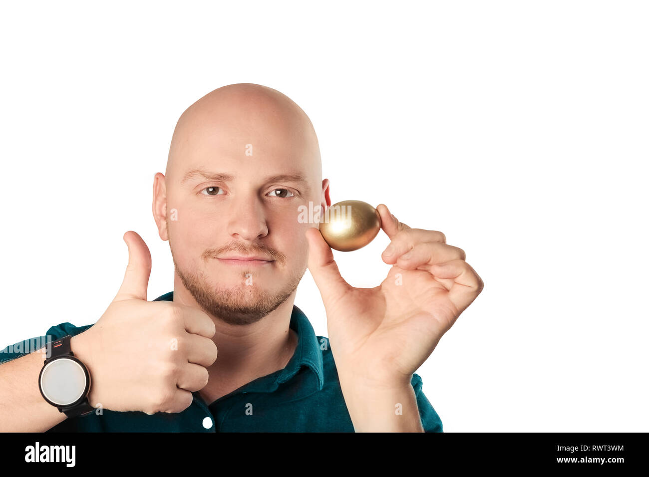 Joven con camisa azul la celebración de huevos de oro a la cámara, la sensación de confianza., sintiéndose seguros. Foto de estudio sobre un fondo blanco. Foto de stock