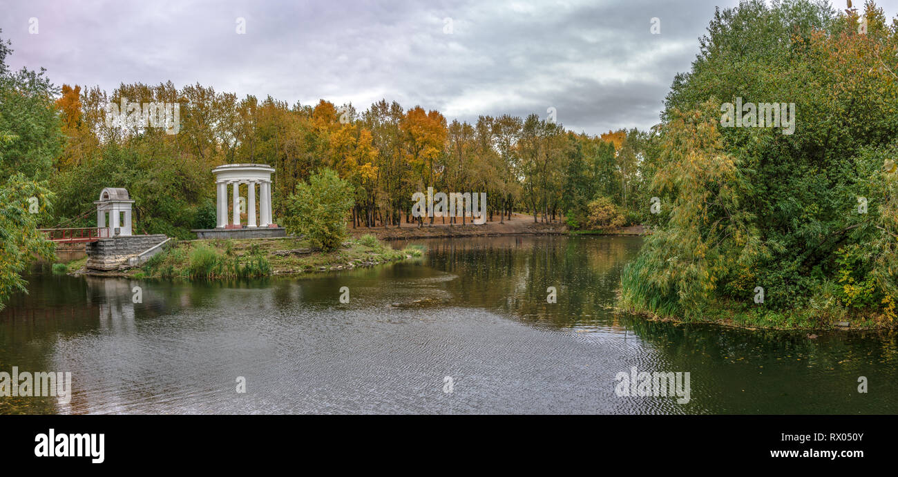 Estanque en un parque verde de la ciudad con una rotonda a principios de otoño Foto de stock
