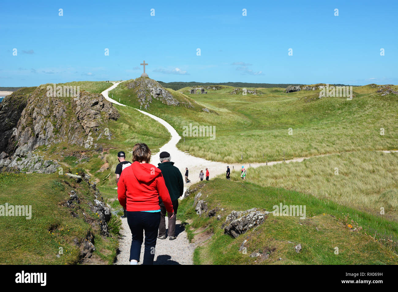 Caminando hacia la cruz del faro en la isla Llanddwyn Foto de stock