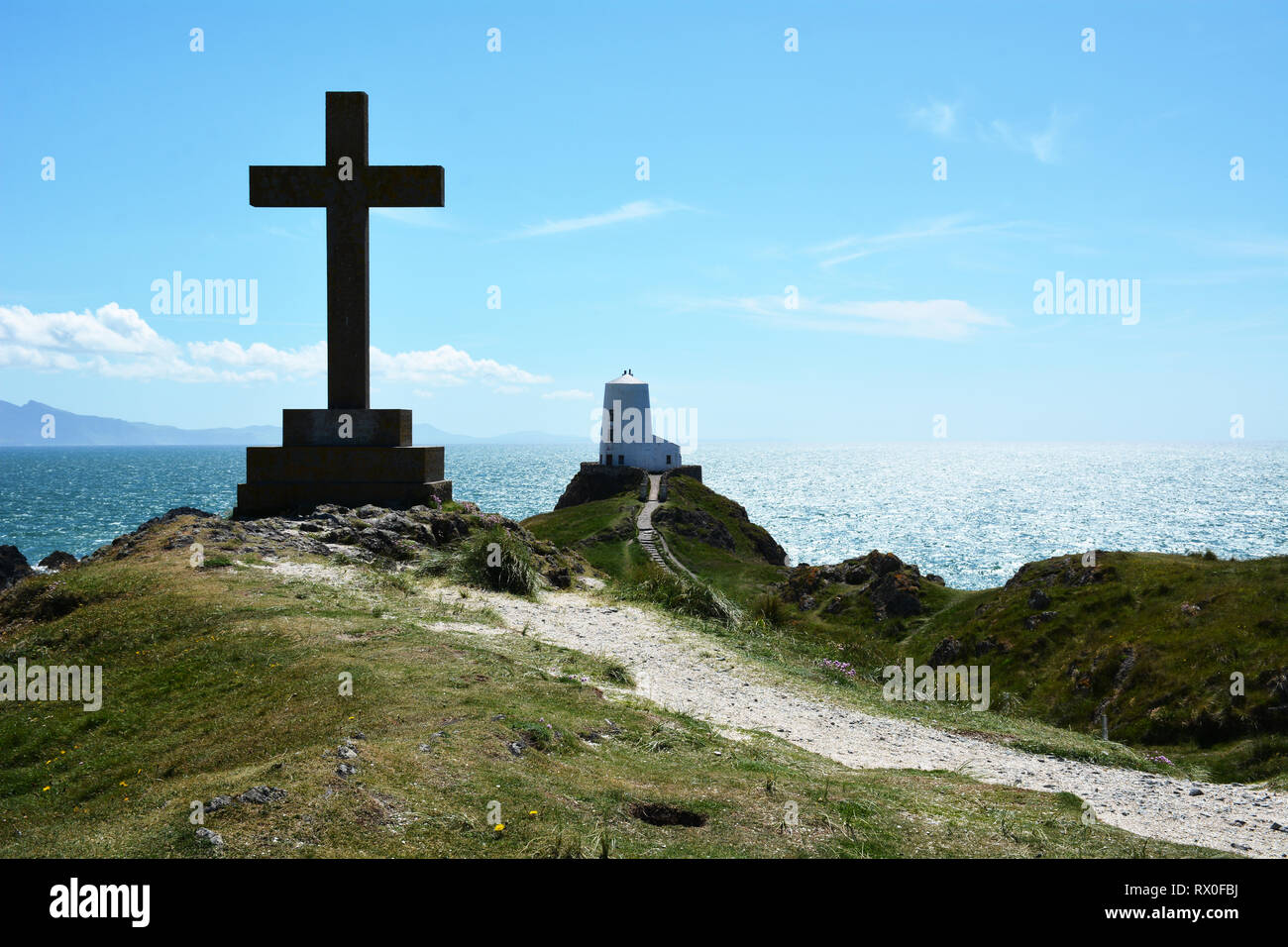 La cruz y Twr Mawr faro en Llanddwyn isla frente a la costa sur oeste de Anglesey en el norte de Gales. Foto de stock