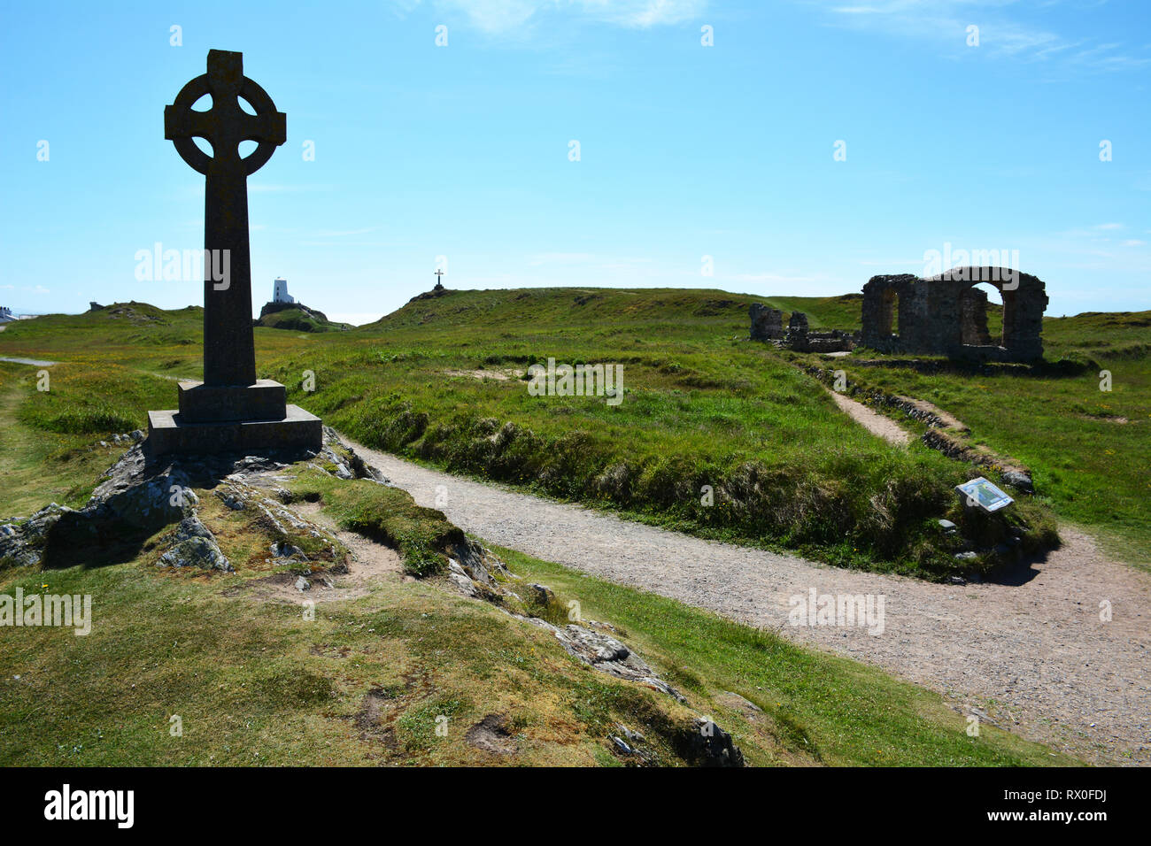 Las cruces, la iglesia y el faro en la isla Llanddwyn frente a la costa de Anglesey Foto de stock