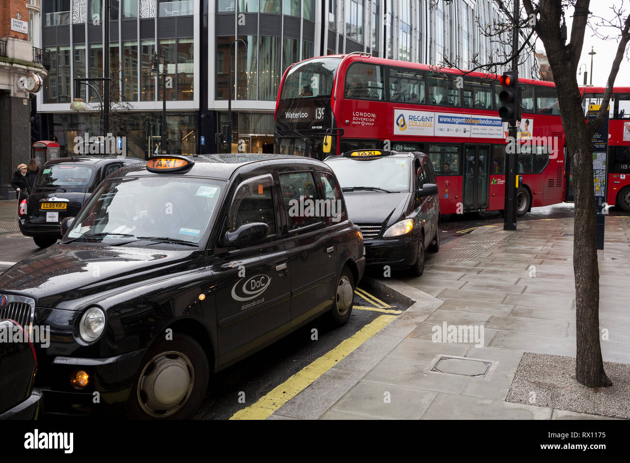 Con los motores en marcha, tradicional black cabs cola para tarifas, por consiguiente bloqueando el tráfico del bus fuera el Selfridge's department store en Oxford Street, el 4 de marzo de 2019, en Londres, Inglaterra. Foto de stock