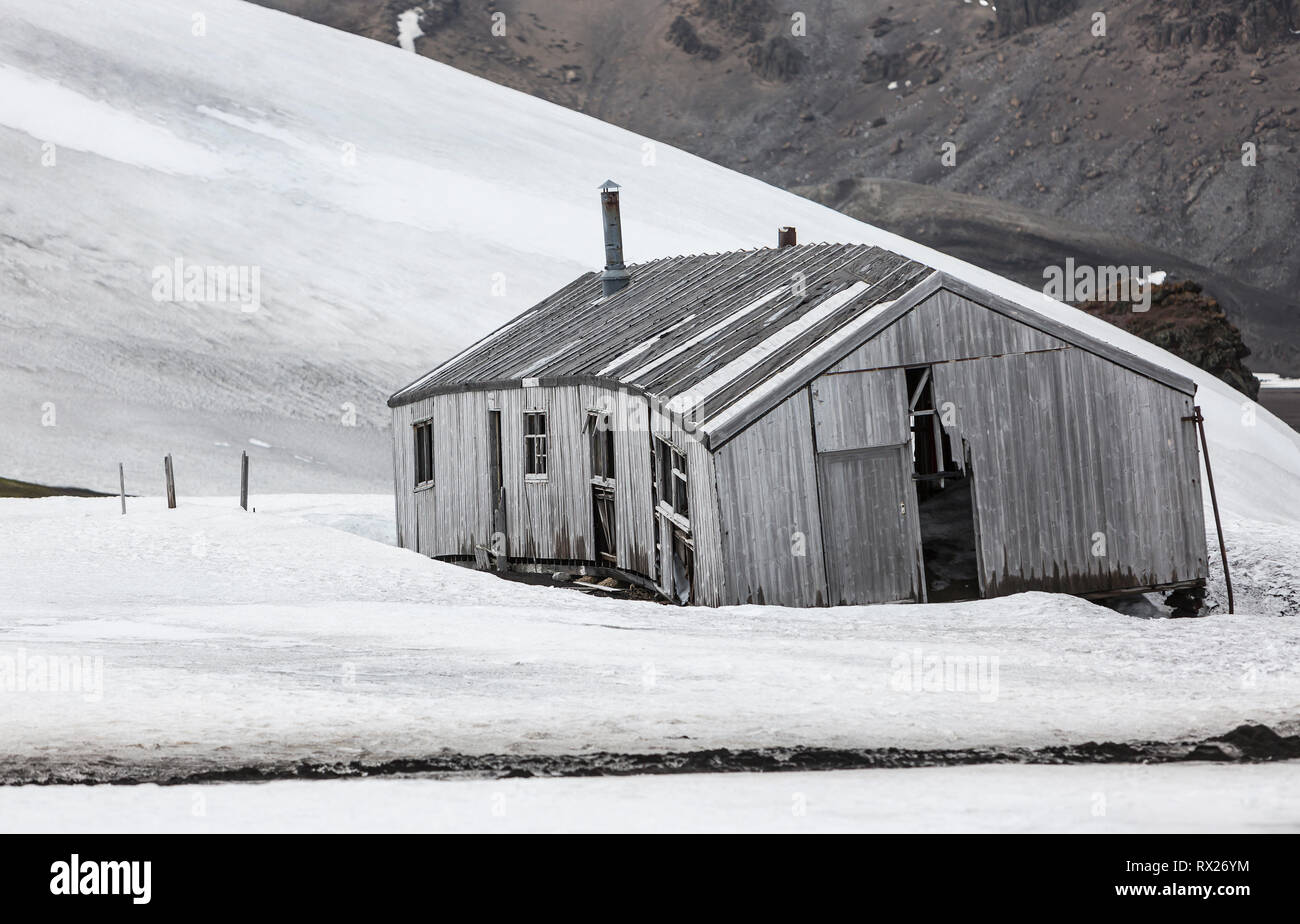 Una caseta abandonada entre un campo de nieve se deteriora lentamente en el clima áspero de Whalers Bay. Isla decepción, Islas Shetland del Sur, Antártida. Foto de stock