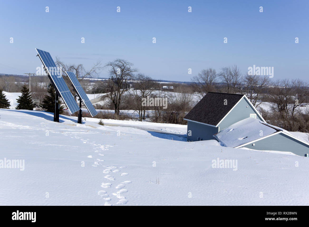 Casa cubierta de la tierra con paneles solares fotovoltaicos en un entorno rural de invierno. Foto de stock