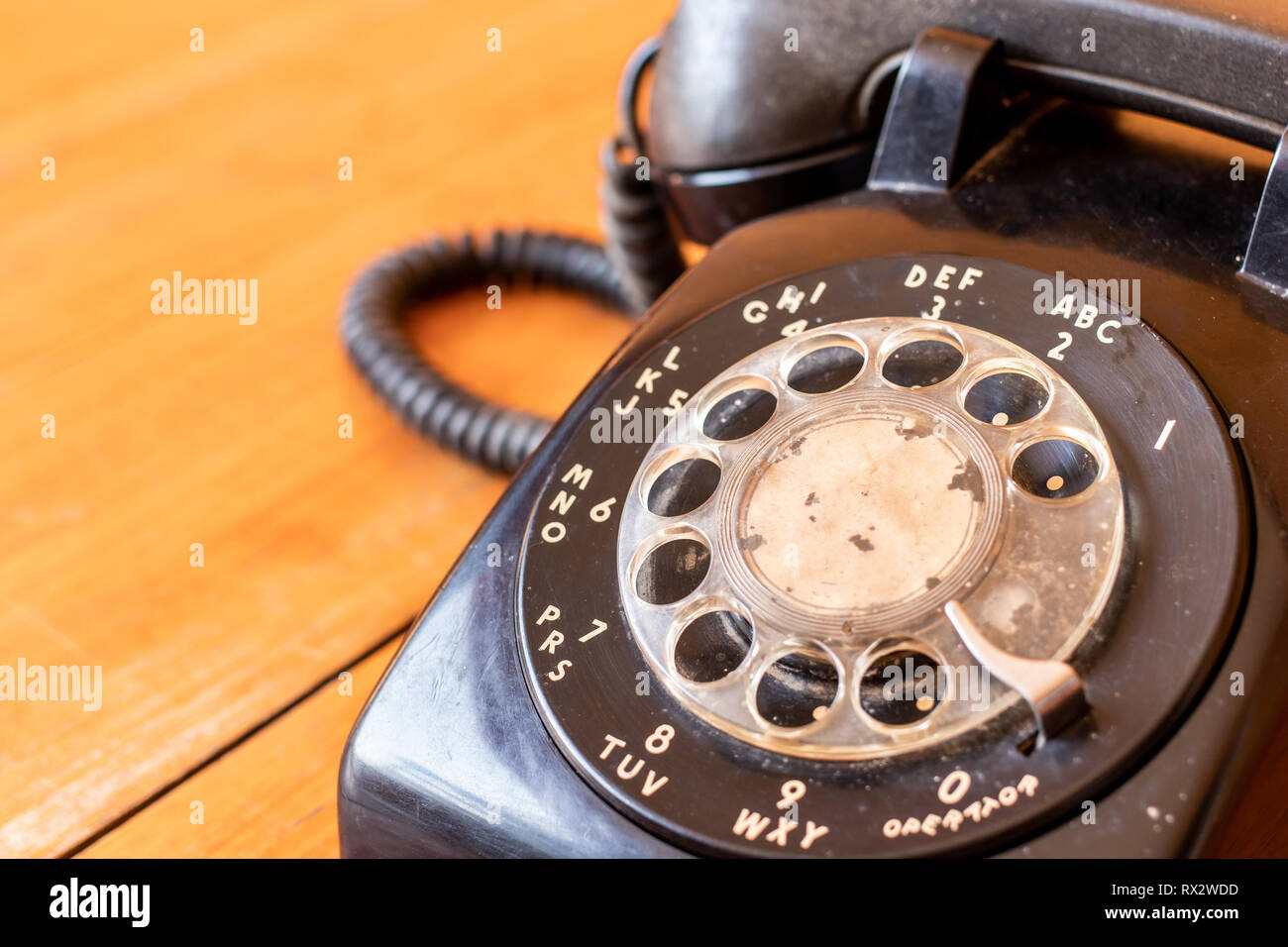 Teléfono Retro negro antiguo giratorio colocado sobre una mesa de madera. Foto de stock